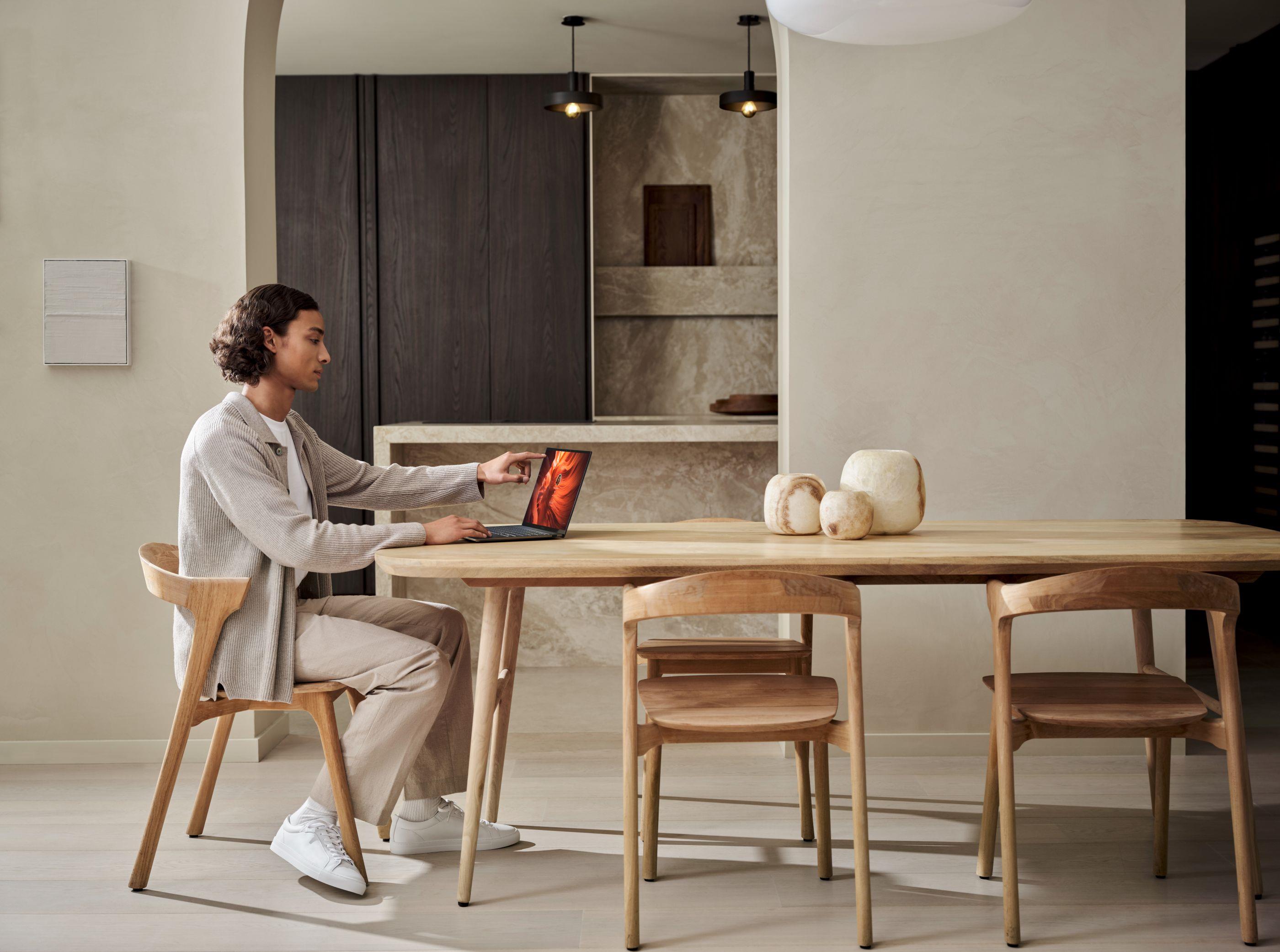 A person sitting at a table using an ASUS Zenbook S14